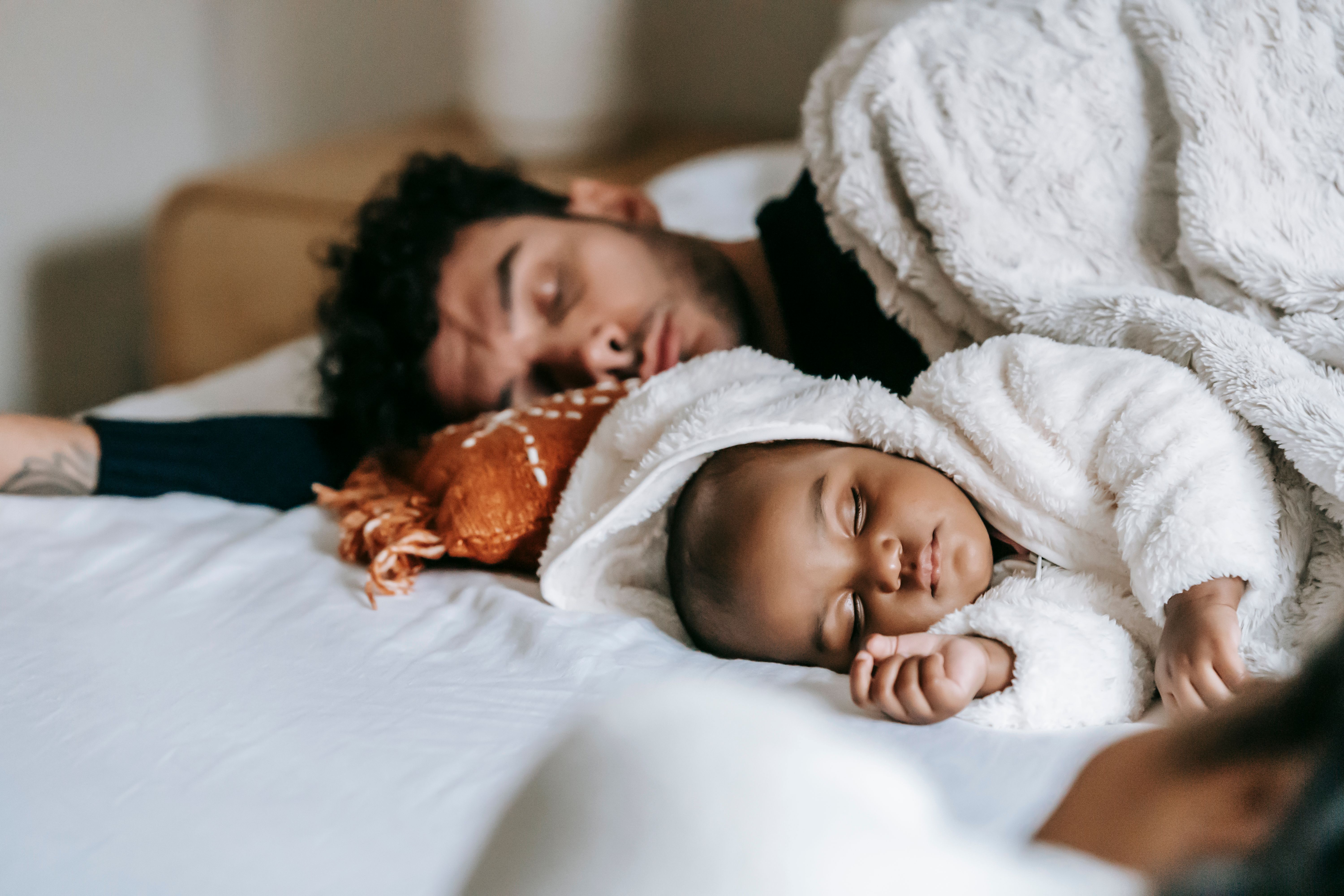 Father and baby sleeping side by side in bed